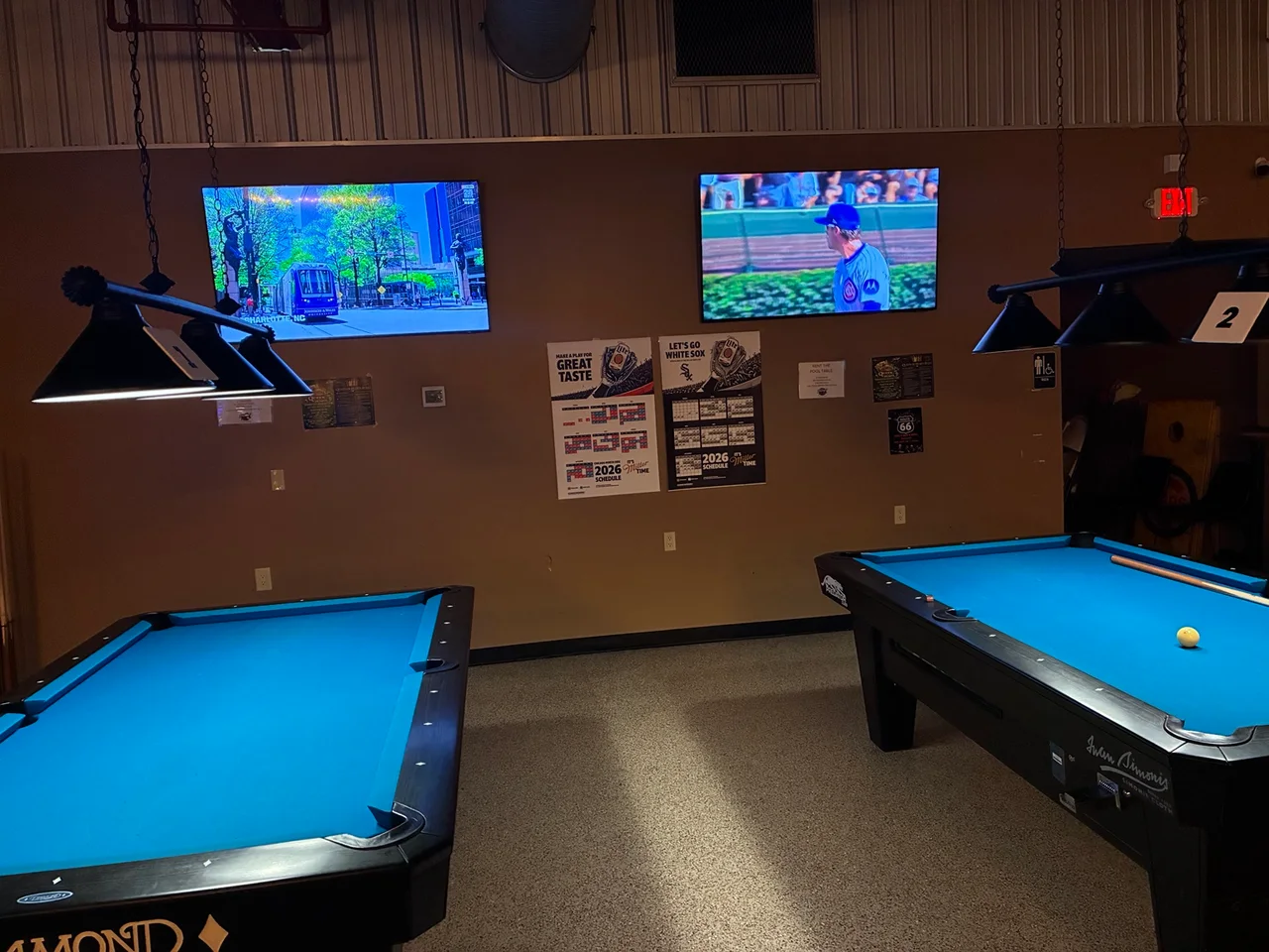 The two pool tables at Kings with overhead lights and televisions